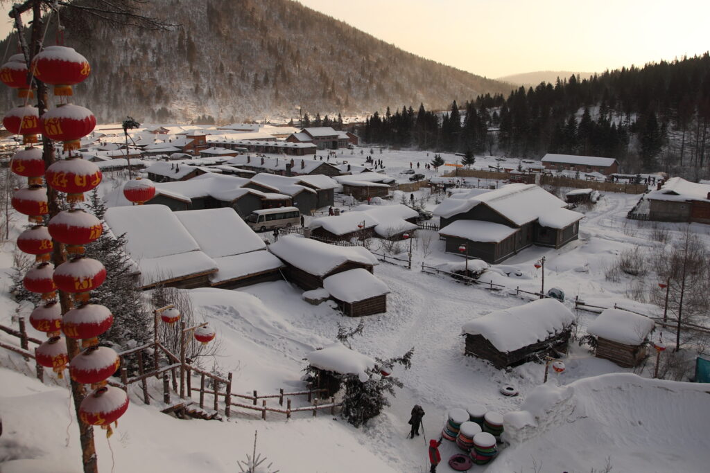 Snow-covered wooden cabins on a winter morning in China Snow Town