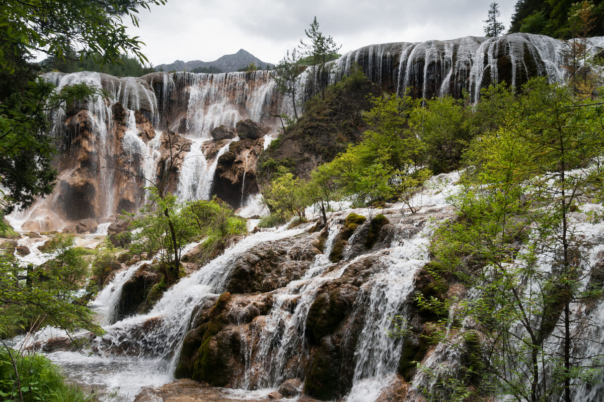 Pearl Shoals Waterfall cascading through autumn forest in Jiuzhaigou Valley